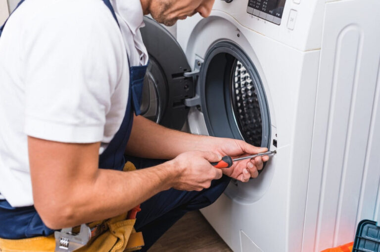 Technician performing washing machine repair on a front-load washer with professional tools