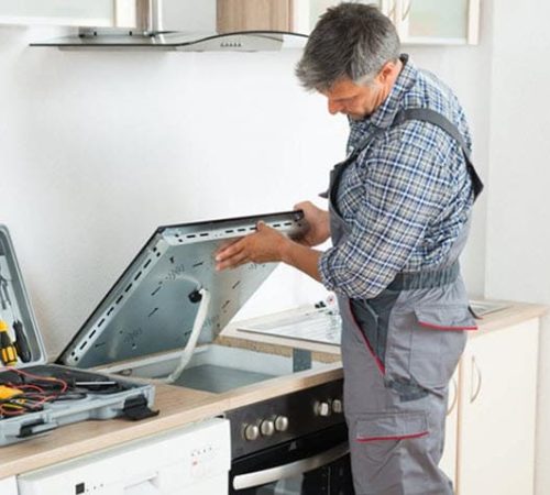 Technician performing professional oven repair service while inspecting a kitchen range appliance