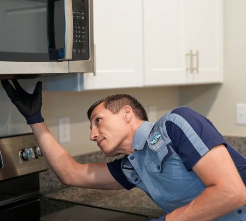 Serenity Appliance Repair technician inspecting an over-the-range microwave during kitchen appliance repair service