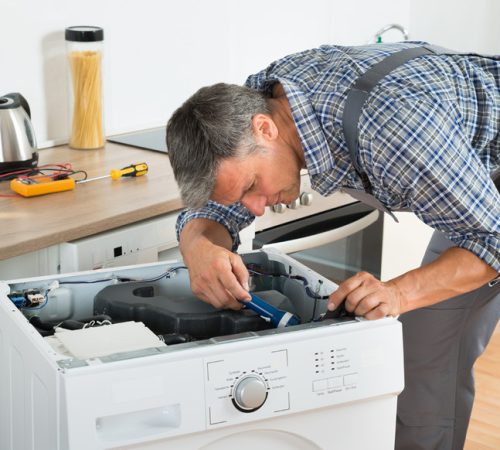 Technician performing professional washing machine repair with diagnostic tools