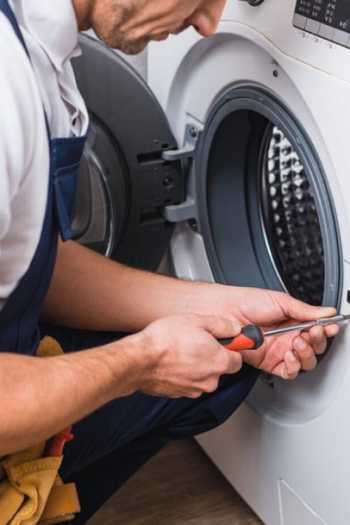 Technician performing washing machine repair on a front-load washer with professional tools